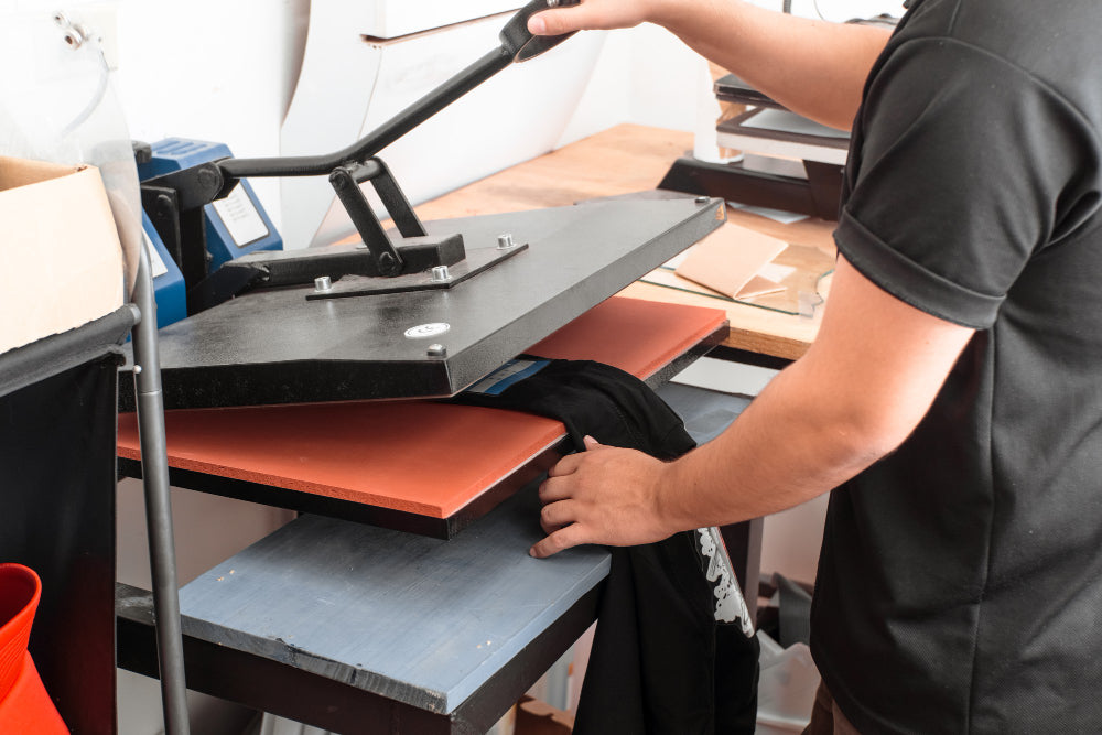 A heat press closing on a dark T-shirt